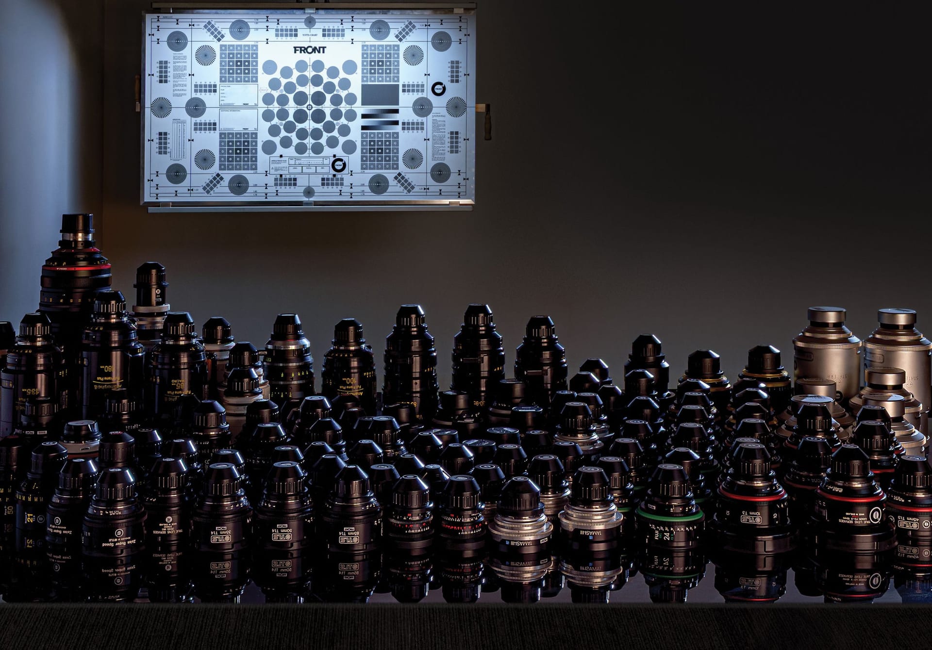 The Front’s cinema lens collection arranged beneath a back-lit resolution test chart in the Banksmeadow test room